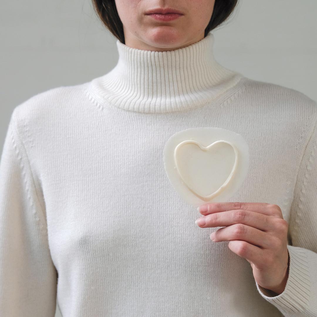 A woman holding a waxy thin heart shape