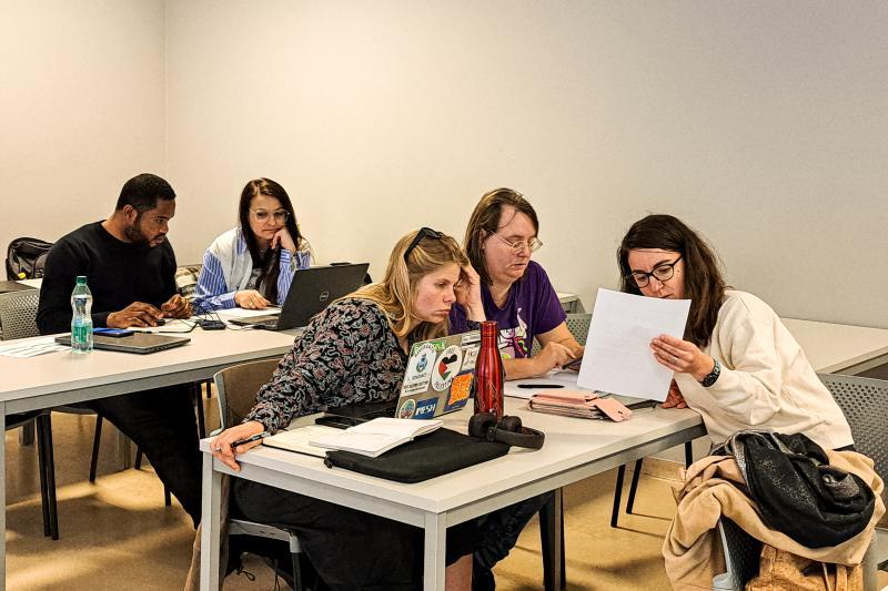 Teams of university students discuss a project