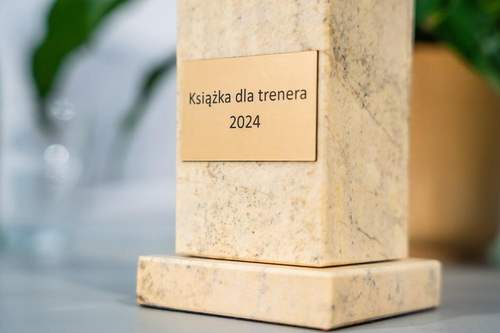 Close-up of gold badge with inscription: Book for trainer