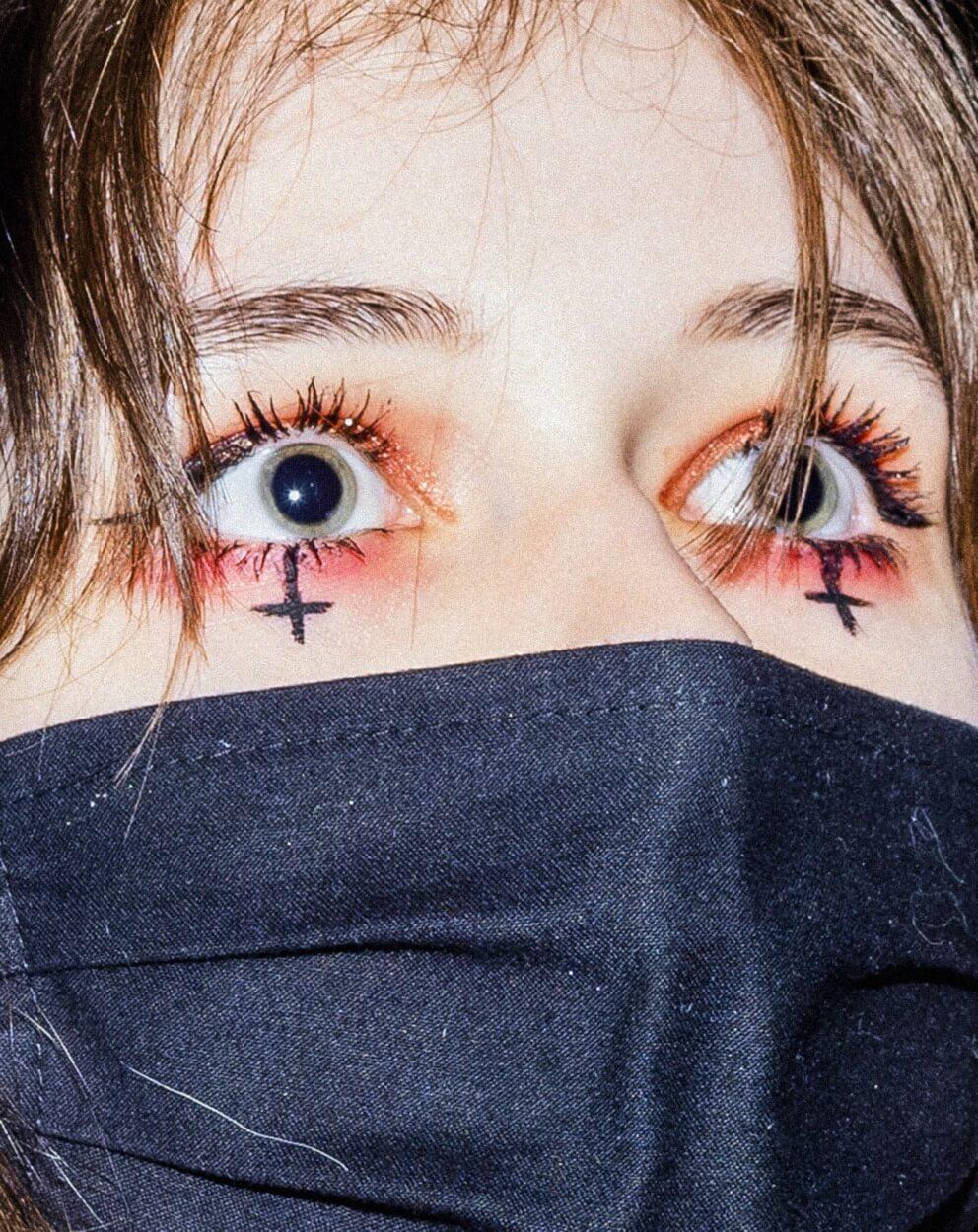 Portait photo of a masked young woman with inverted crosses under her eyes protesting against strict abortion law in Poland