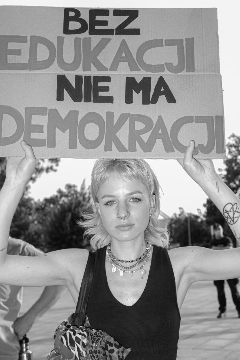 Young woman at a protest holding a sign that reads: 'There is no education without democracy.'