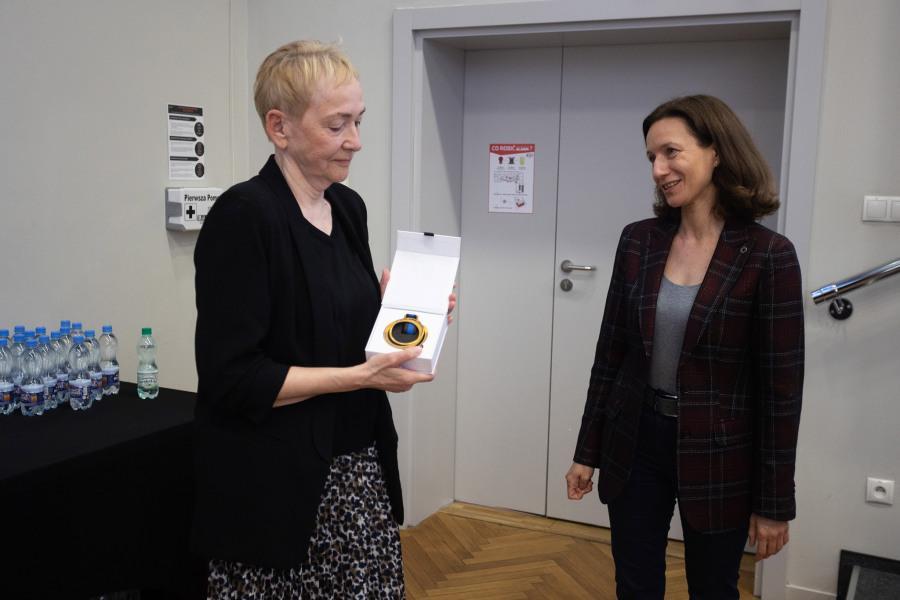 Professor Aleksandra Cisłak-Wójcik is looking at Professor Krystyna Drat-Ruszczak, who is holding a Medal of SWPS University