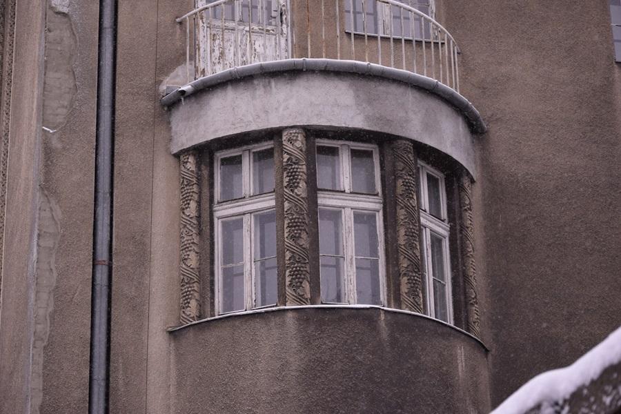 Close-up of three windows of the building. Between each window, there is decorative embossing depicting grapes.