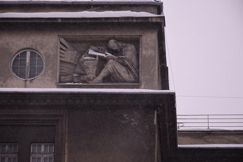 Bas-relief depicting one of the evangelists reading a book. The figure is dressed in a robe, and at its bare feet rests the head of a cow.